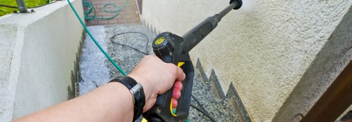 Person reinigt Fassade mit Hochdruckreiniger